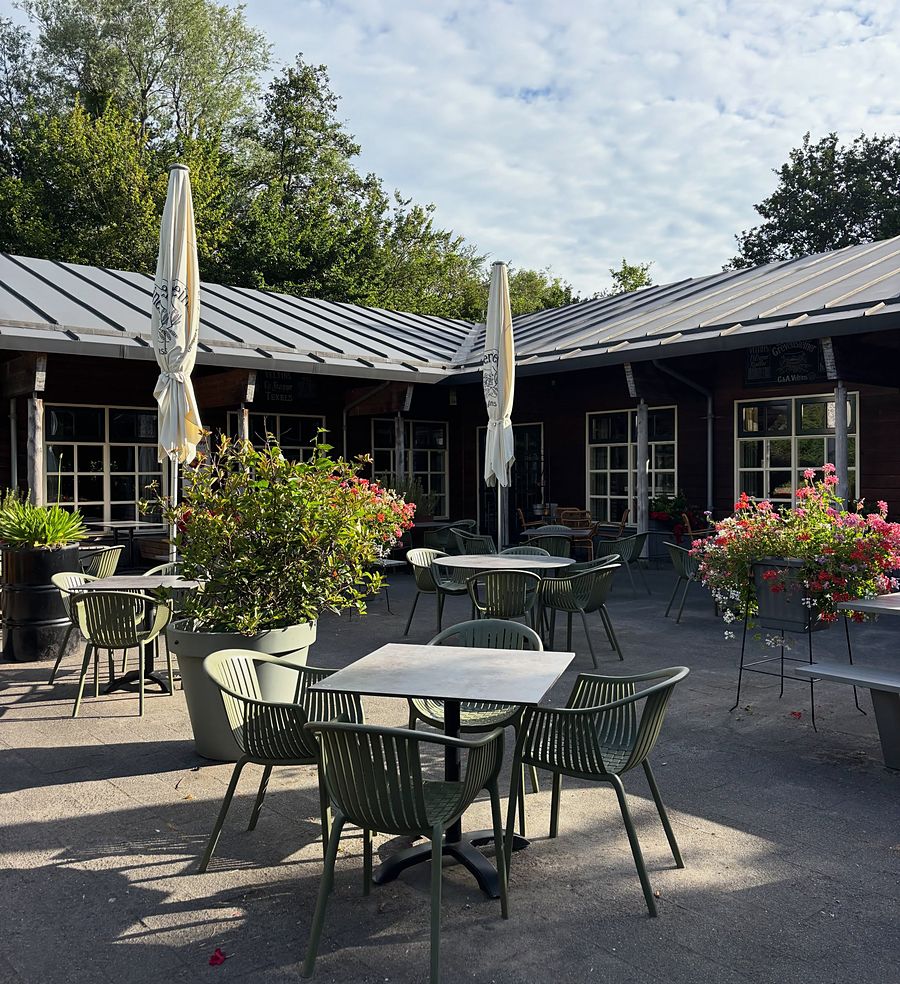 Het terras van De Meidoorn in de zon, met de parasols en het houten paviljoen